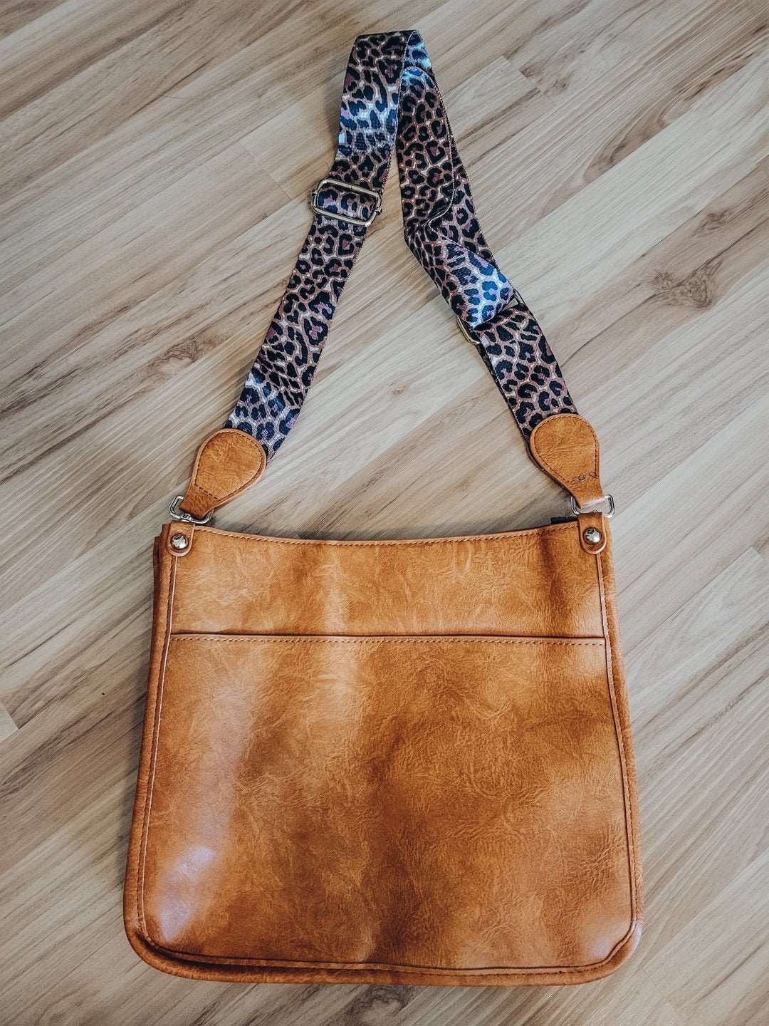 Light brown crossbody handbag with leopard strap.