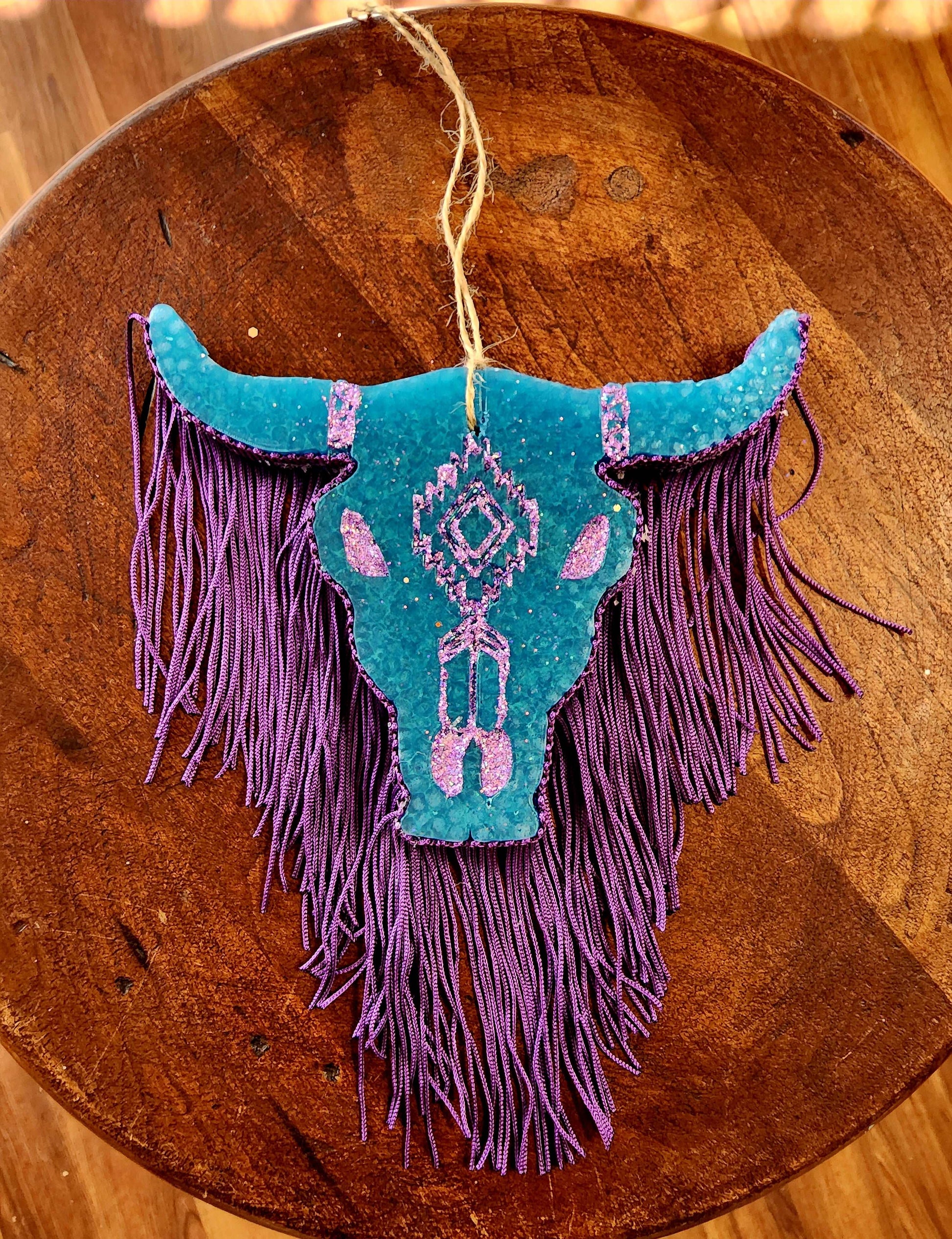 Blue bull skull car freshie with purple glitter and fringe in scent baja cactus.