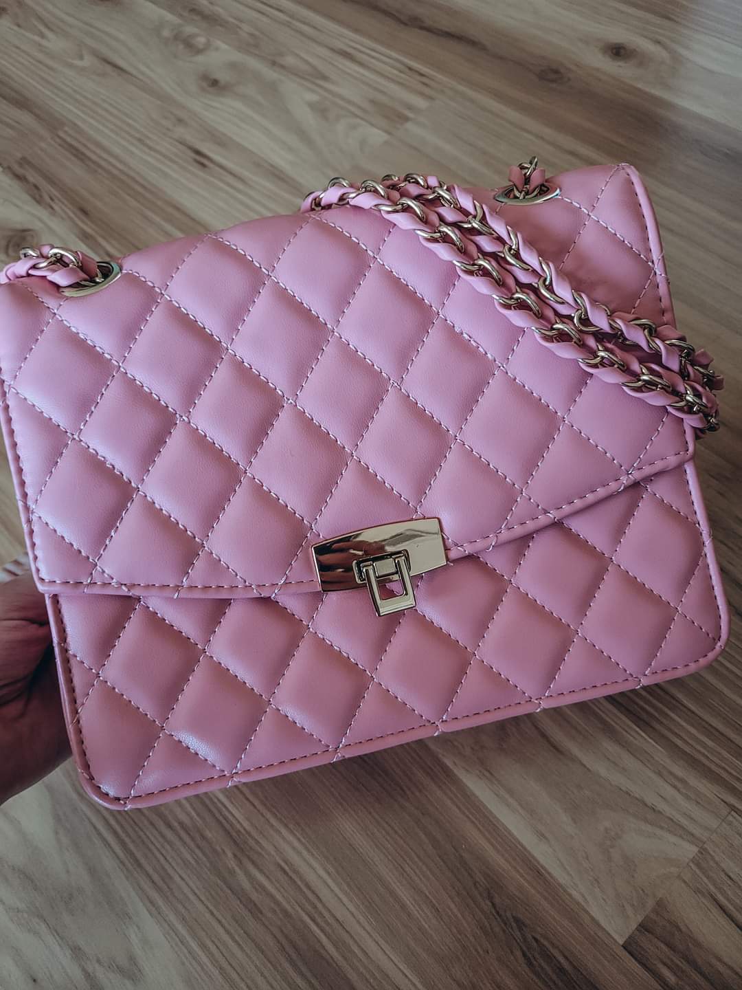 Pink quilted purse with pink and gold chain strap. 