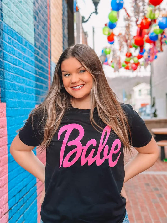 Black tee with hot pink puff ink with word Babe on it. 